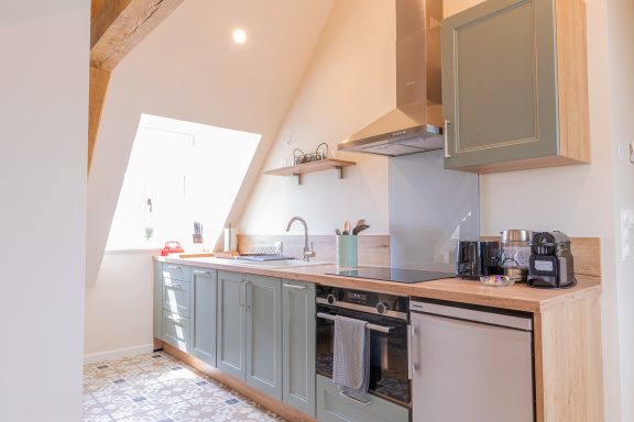 Cuisine Küche mit Holzoberflächen, modernen Geräten und viel Tageslicht durch ein Dachfenster.